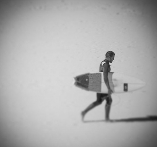 surfista caminando con su tabla por la playa